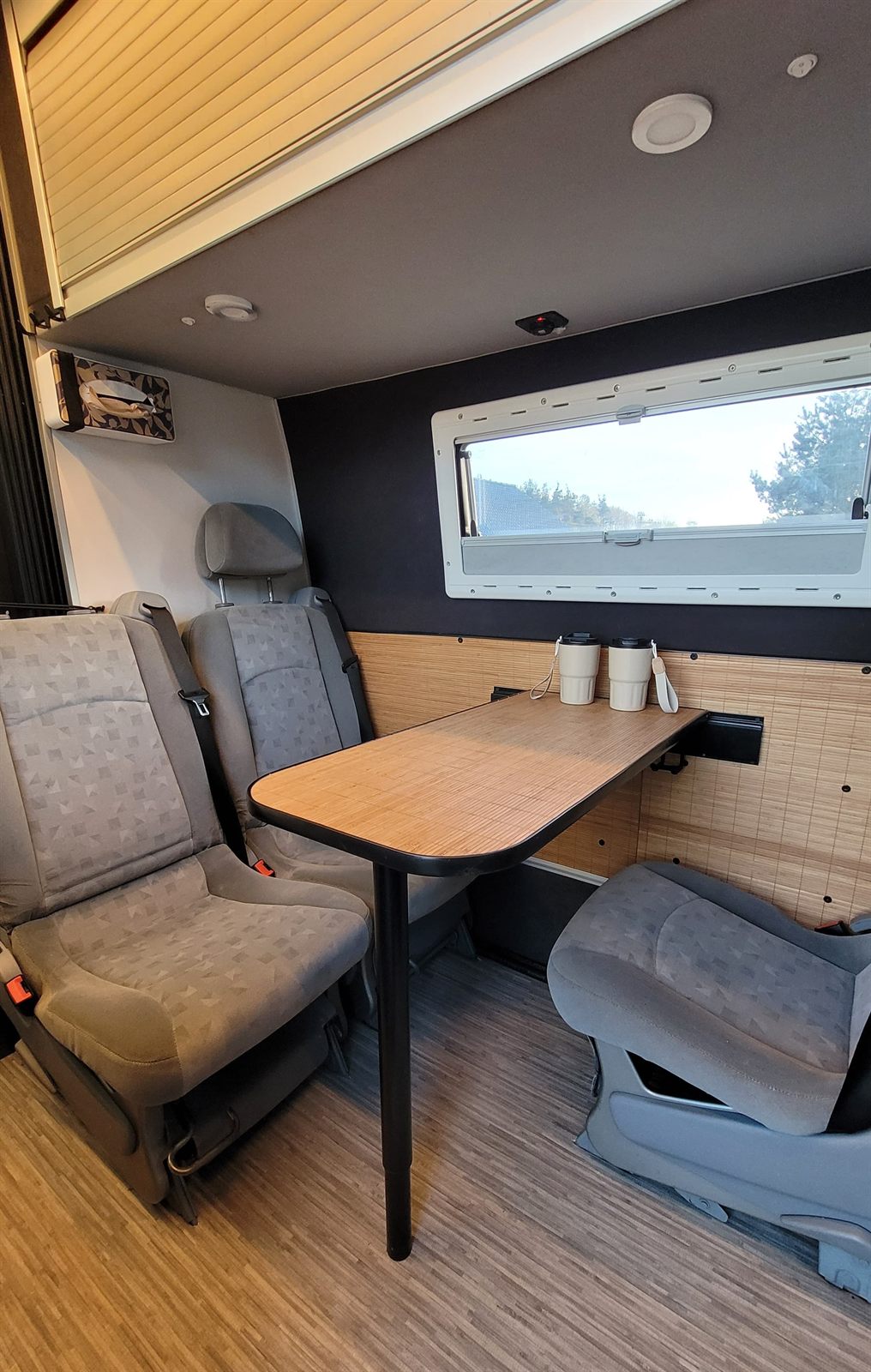 Obrotowe fotele i stół przy oknie we wnętrzu Iveco Daily