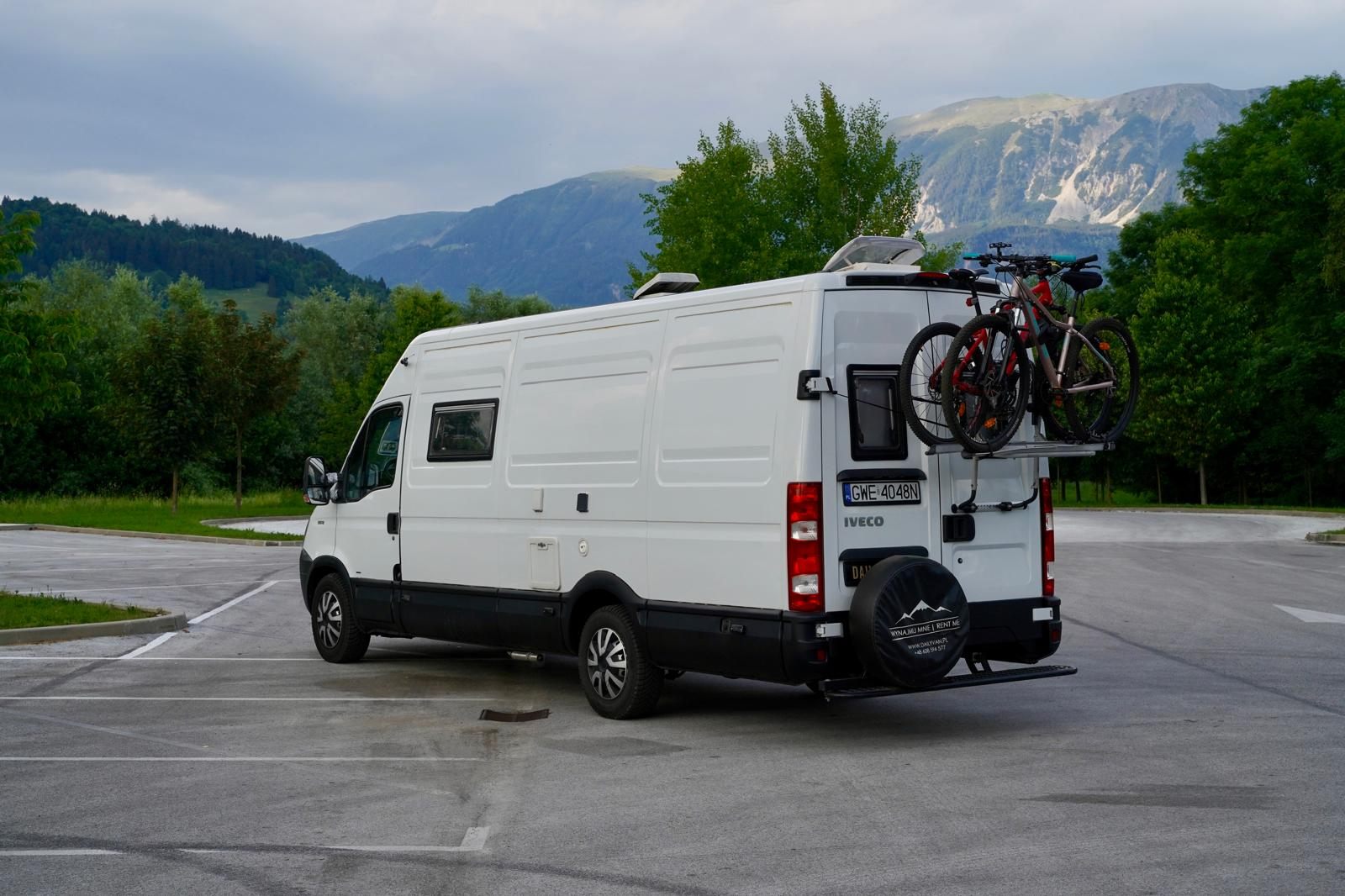 Iveco Daily zaparkowany na tle gór, z rowerem na tylnym bagażniku
